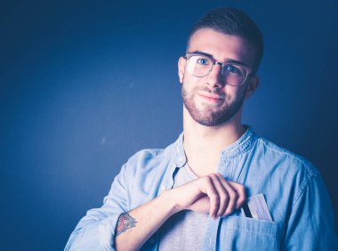 Gri arka planda duran bir kredi kartı tutan genç adam. Genç girişimci..