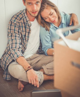 Genç bir çift yeni ev içinde hareket. Oturma ve açma sonra rahatlatıcı. Bir şey üstünde laptop arıyorum. Genç Çift