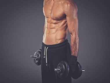 Yakışıklı kaslı adam dumbell ile çalışma dışarı. Kişisel fitness eğitmeni. Kişisel eğitim.