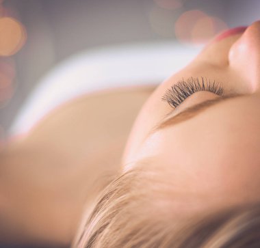 Masaj masasında uzanmış gözleri kapalı rahatlayan genç bir kadın. - Kadın. Spa salonu