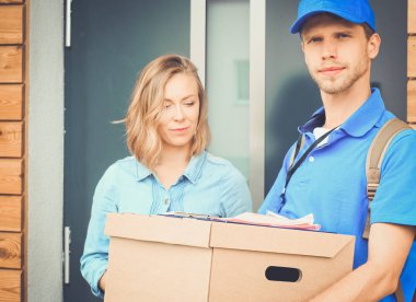 Mavi üniformalı gülümseyen kurye servis konseptine paket kutusu teslim eden teslimatçı. Mavi üniformalı gülümseyen teslimatçı.