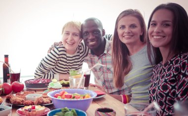 Ahşap masada otururken birlikte yemek yiyen bir grup insanın üst düzey görüntüsü. Masada yemek var. İnsanlar fast food yiyor..