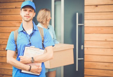 Mavi üniformalı gülümseyen kurye servis konseptine paket kutusu teslim eden teslimatçı. Mavi üniformalı gülümseyen teslimatçı.