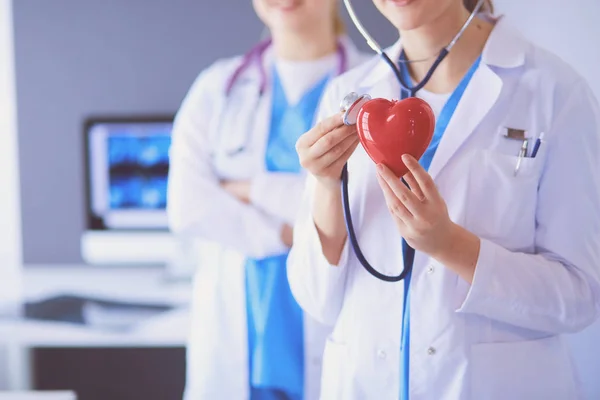 Pouls recadré de deux jeunes médecins femelle avec stéthoscope tenant le cœur. — Photo