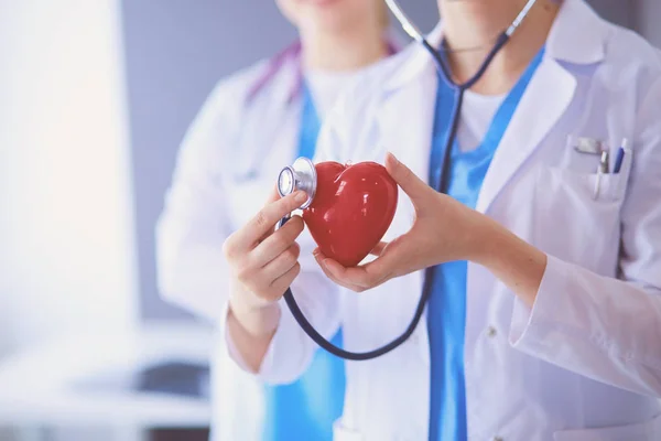 Abgeschnittene Aufnahme zweier junger Ärztinnen mit Stethoskop am Herzen. — Stockfoto