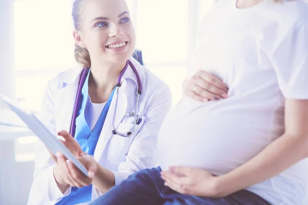 Leende kvinnlig läkare visar bilder på tabletten för gravida unga kvinnor på sjukhuset. — Stockfoto