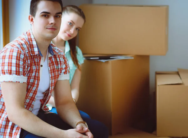 Couple moving in house sitting on the floor. Couple