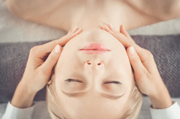 Mujer joven acostada en una mesa de masaje, relajándose con los ojos cerrados. Una mujer. Salón de spa — Foto de Stock