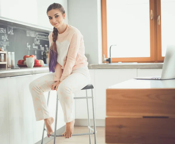 Jeune femme assise sur la table dans la cuisine . — Photo