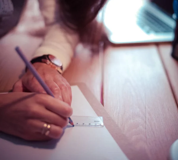 Een jonge vrouw die aan een bureau zit. Zakenvrouw. Tekenen. Studente. Werkplaats. Bureau. — Stockfoto