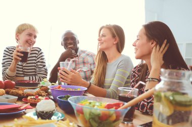 Ahşap masada otururken birlikte yemek yiyen bir grup insanın üst düzey görüntüsü. Masada yemek var. İnsanlar fast food yiyor..