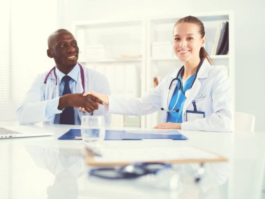 Ofiste tokalaşırken gülümseyen iki genç tıp adamı. Doktorlar. Takım çalışması.