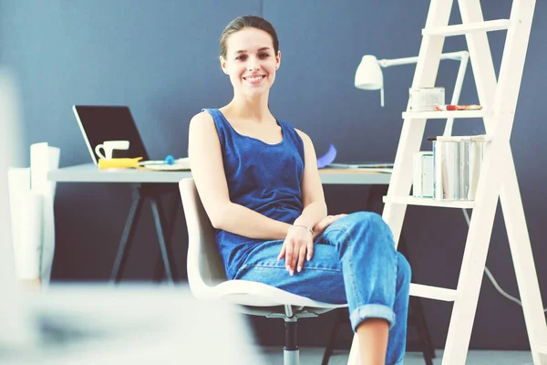 Jonge vrouw zit aan het bureau met instrumenten, plan en laptop. — Stockfoto