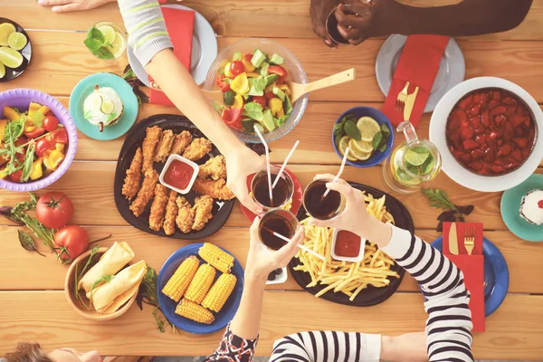 Top view of group of people having dinner together while sitting at wooden table. Food on the table. People eat fast food. — Stock Photo, Image