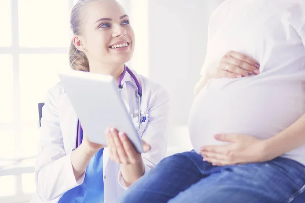 Il medico sorridente mostra le immagini sulla compressa a una giovane donna incinta in ospedale. — Foto Stock