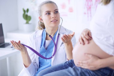 Steteskoplu genç bayan doktor hastanede hamile bir kadınla konuşuyor..