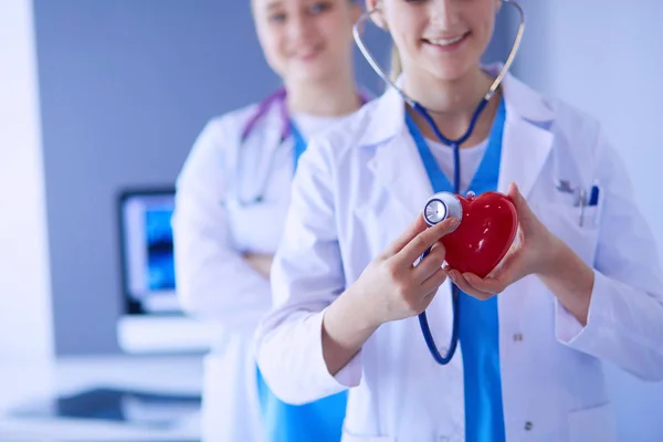 Cropped shoot of two young doctors female with stethoscope holding heart. — Stock Photo, Image