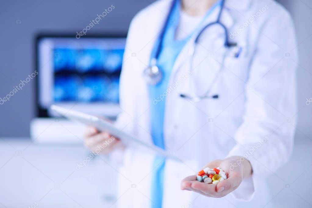 Close-up shot of doctors hands holding pills and tablet at clinic.
