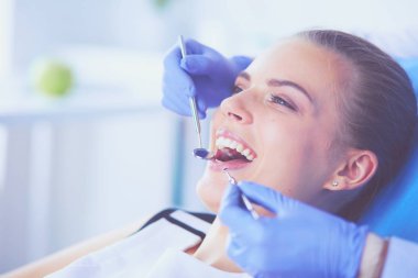 Dişçi muayenehanesinde diş muayenesi yapan ağzı açık genç bir kadın hasta..