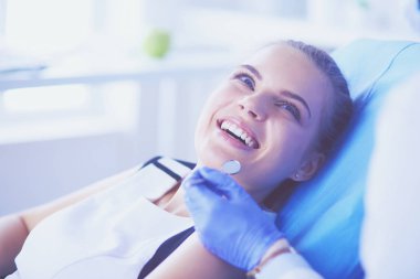 Güzel gülüşü olan genç bir bayan hasta dişçi muayenesi için dişçiye gidiyor..