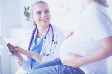 Gülümseyen kadın doktor resimlerini tablette hastanedeki hamile genç bayana gösteriyor..