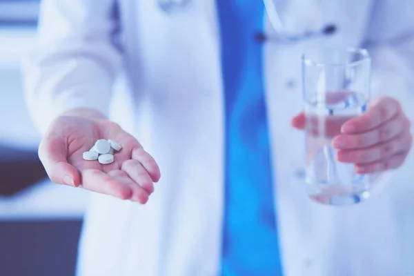 Снимок рук врачей с таблетками и стаканом воды в клинике. — стоковое фото
