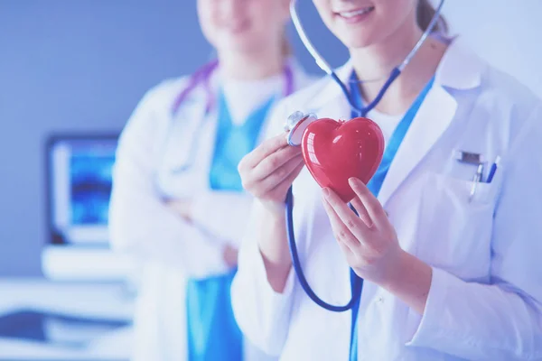 Обрізаний знімок двох молодих лікарів-жінок зі стетоскопом, що тримає серце . — стокове фото