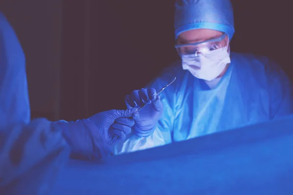 Médico realizando cirugía en un fondo oscuro. — Foto de Stock