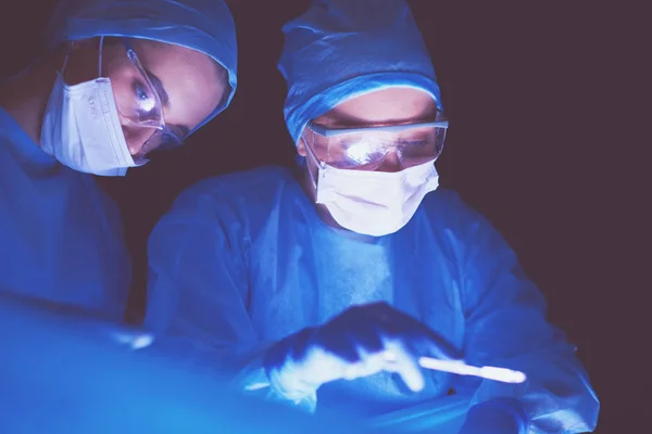 Imagen recortada del bisturí tomada médicos que realizan la cirugía. — Foto de Stock