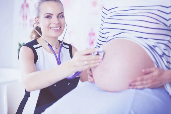 Portret van een jonge vrouwelijke arts die een zwangere vrouw onderzoekt in de kliniek. — Stockfoto