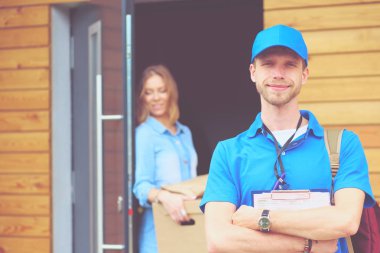 Mavi üniformalı gülümseyen kurye servis konseptine paket kutusu teslim eden teslimatçı. Mavi üniformalı gülümseyen teslimatçı.