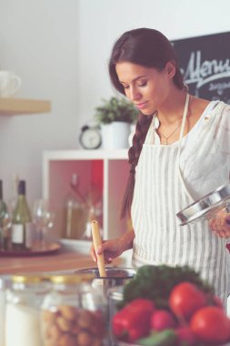 Mutfakta ahşap kaşıkla yemek pişiren kadın. Aşçı kadın.