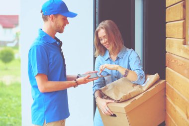 Mavi üniformalı gülümseyen kurye servis konseptine paket kutusu teslim eden teslimatçı. Mavi üniformalı gülümseyen teslimatçı.