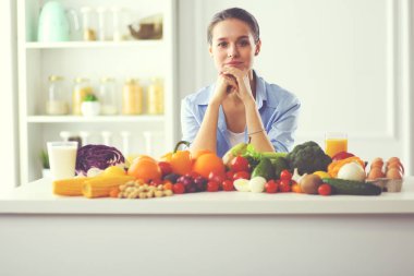 Ahşap iç kısımda meyve ve sebze dolu masada oturan genç ve tatlı bir kadın..