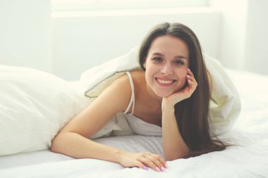 Güzel bir kadın yatağında uzanıyor..
