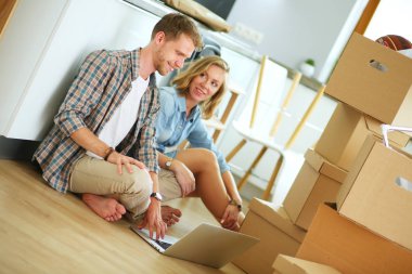 Genç bir çift yeni ev içinde hareket. Oturma ve açma sonra rahatlatıcı. Bir şey üstünde laptop arıyorum. Genç Çift