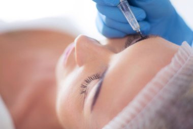 Kaşlar için kalıcı makyaj. Güzellik salonunda kalın kaşlı güzel bir kadın..