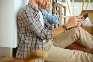 Genç bir çift yeni ev içinde hareket. Oturma ve açma sonra rahatlatıcı. Bir şey üstünde laptop arıyorum. Genç Çift