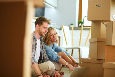 Genç bir çift yeni ev içinde hareket. Oturma ve açma sonra rahatlatıcı. Bir şey üstünde laptop arıyorum. Genç Çift