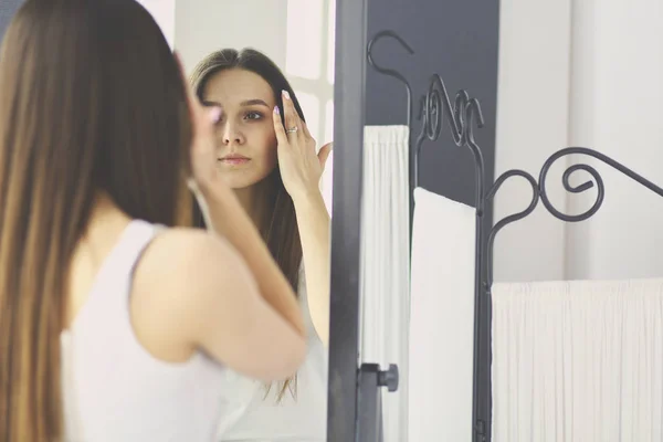 Молода жінка дивиться на себе відображення в дзеркалі вдома . — стокове фото