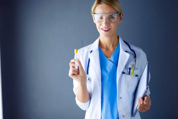 Femmina medico o ricercatore o medico utilizzando guardando una provetta di soluzione limpida in un laboratorio o laboratorio . — Foto Stock