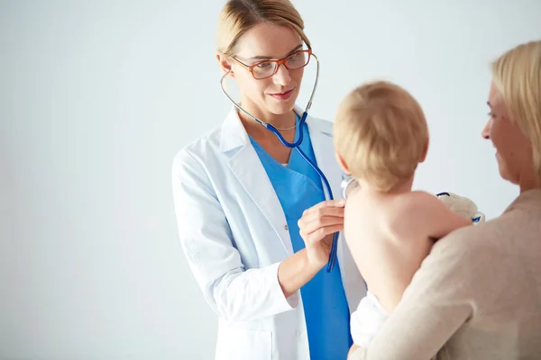 Kobieta lekarz słucha dziecko ze stetoskopem w klinice — Zdjęcie stockowe