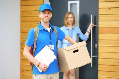 Mavi üniformalı gülümseyen kurye servis konseptine paket kutusu teslim eden teslimatçı. Mavi üniformalı gülümseyen teslimatçı.