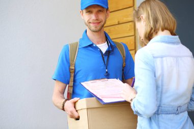 Mavi üniformalı gülümseyen kurye servis konseptine paket kutusu teslim eden teslimatçı. Mavi üniformalı gülümseyen teslimatçı.