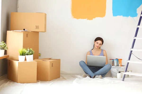 Mladá žena portrét při malování nový byt, sedí s notebookem. Mladá žena s laptopem — Stock fotografie