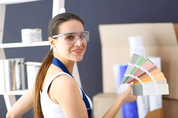 Mujer joven sosteniendo una muestra de color con una pintura de pintor  . —  Fotos de Stock