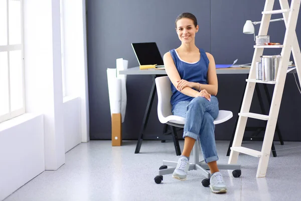 Jonge vrouw zit aan het bureau met instrumenten, plan en laptop. — Stockfoto