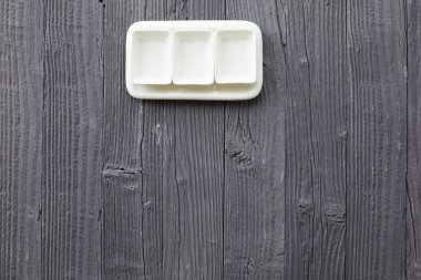 Ahşap masa zemininde kare şeklinde boş seramik tabaklar, üst görünüm.