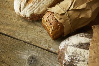 Tahta masanın üzerinde kağıda sarılı bir somun ekmek..