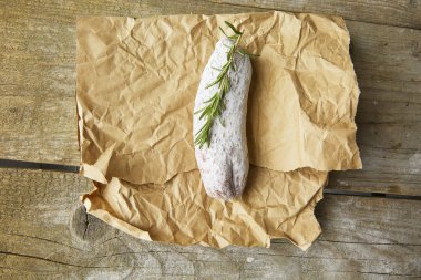 Bütün İtalyan salamı wih Biberiye kağıt üzerinde. Rustik tarzı. Üstten görünüm.